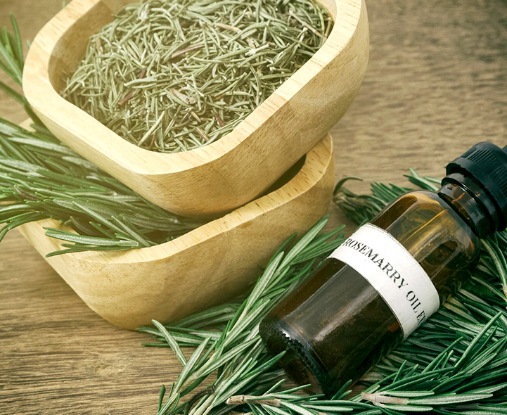 A bottle of rosemary oil next to some wooden bowls.