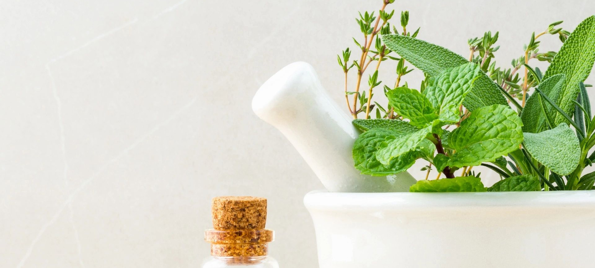 A bottle of essential oil next to a mortar and pestle.